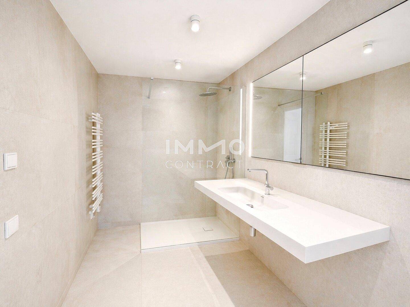 Elegantes Badezimmer mit beigefarbenen Fliesen, moderner Dusche und Handtuchheizkörper.