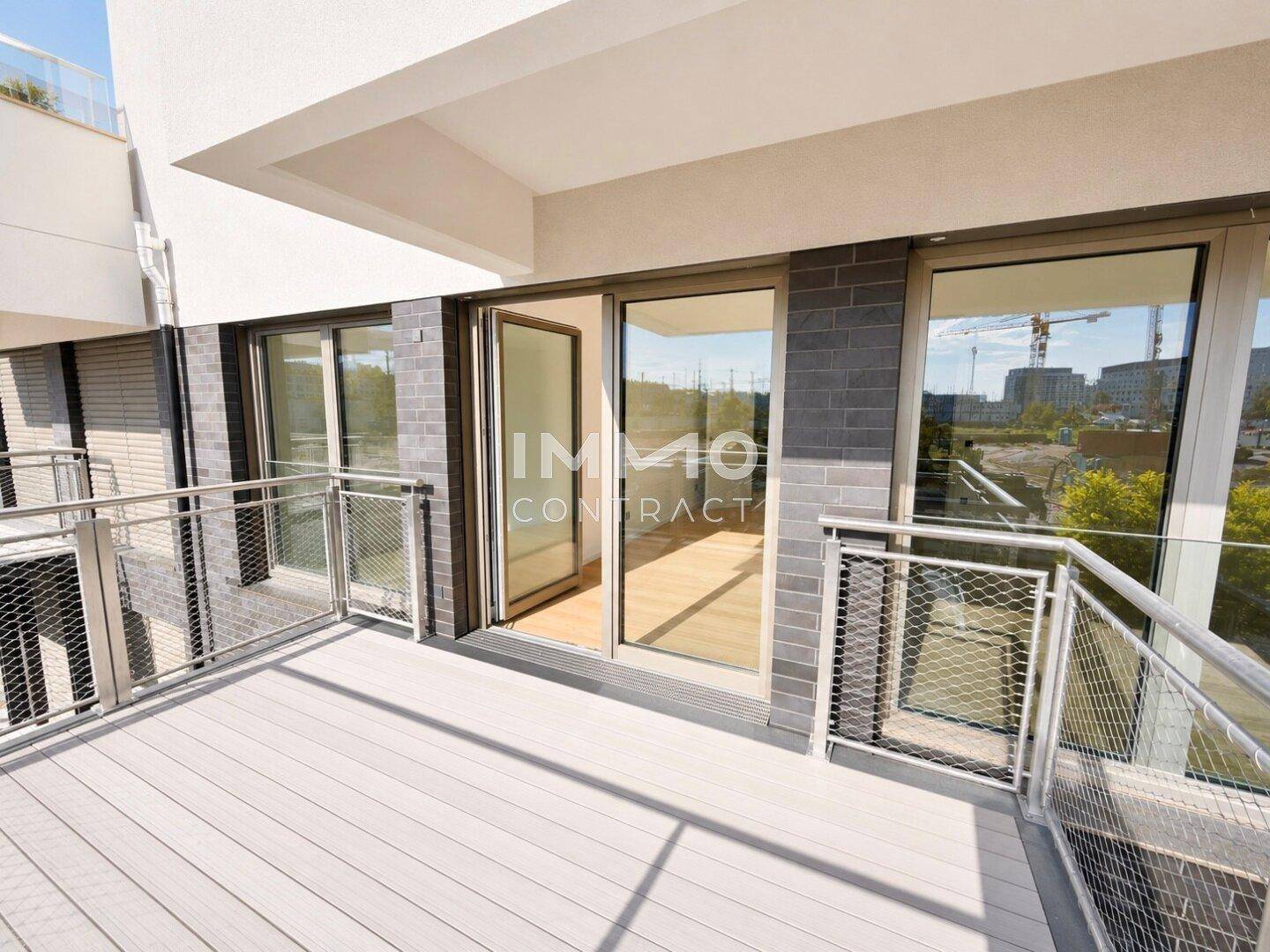 Moderner Balkon mit Metallgeländer und Holzdielen, bietet einen Ausblick auf die Umgebung.