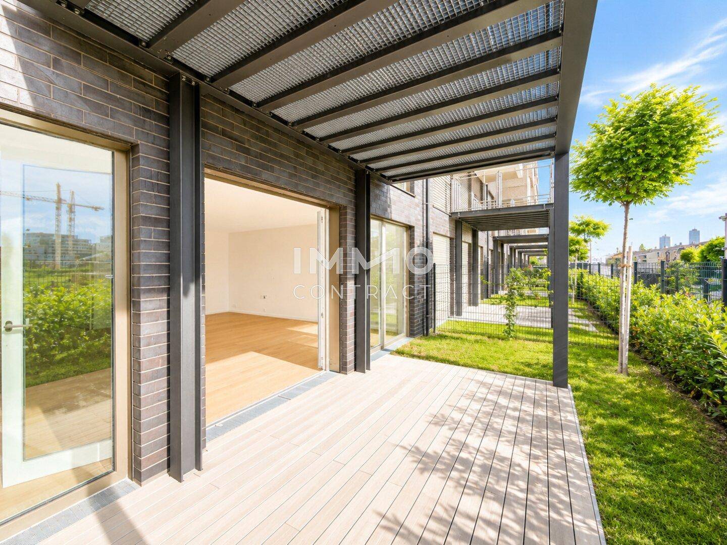 Moderne Terrasse mit Holzdielenboden und Überdachung, umgeben von Grünflächen.