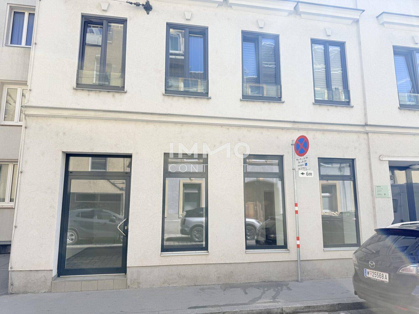 Fassade eines Gebäudes mit großen Fenstern und einem Geschäftseingang im Erdgeschoss an der Straße.