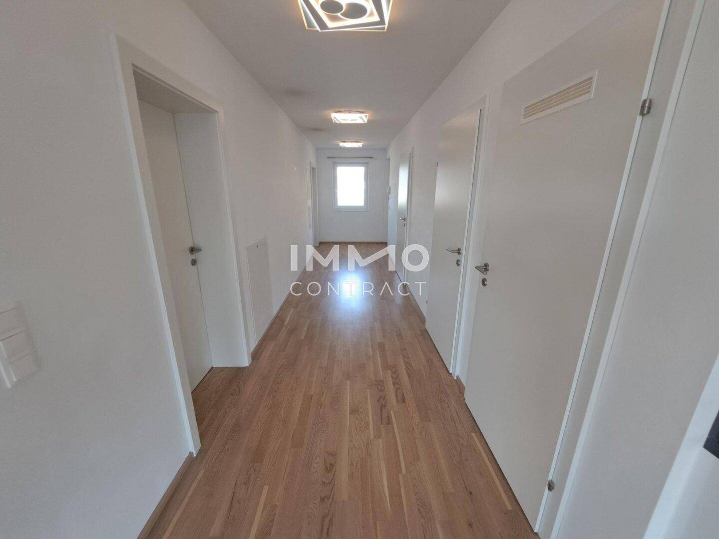Langer, heller Flur mit Holzfußboden und mehreren Türen, der die verschiedenen Zimmer verbindet.