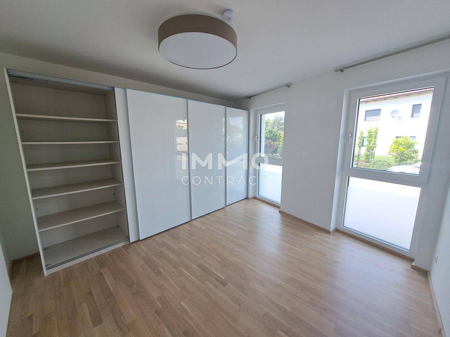 Helles Schlafzimmer mit Holzfußboden, weißen Wänden und praktischen Einbauschränken.