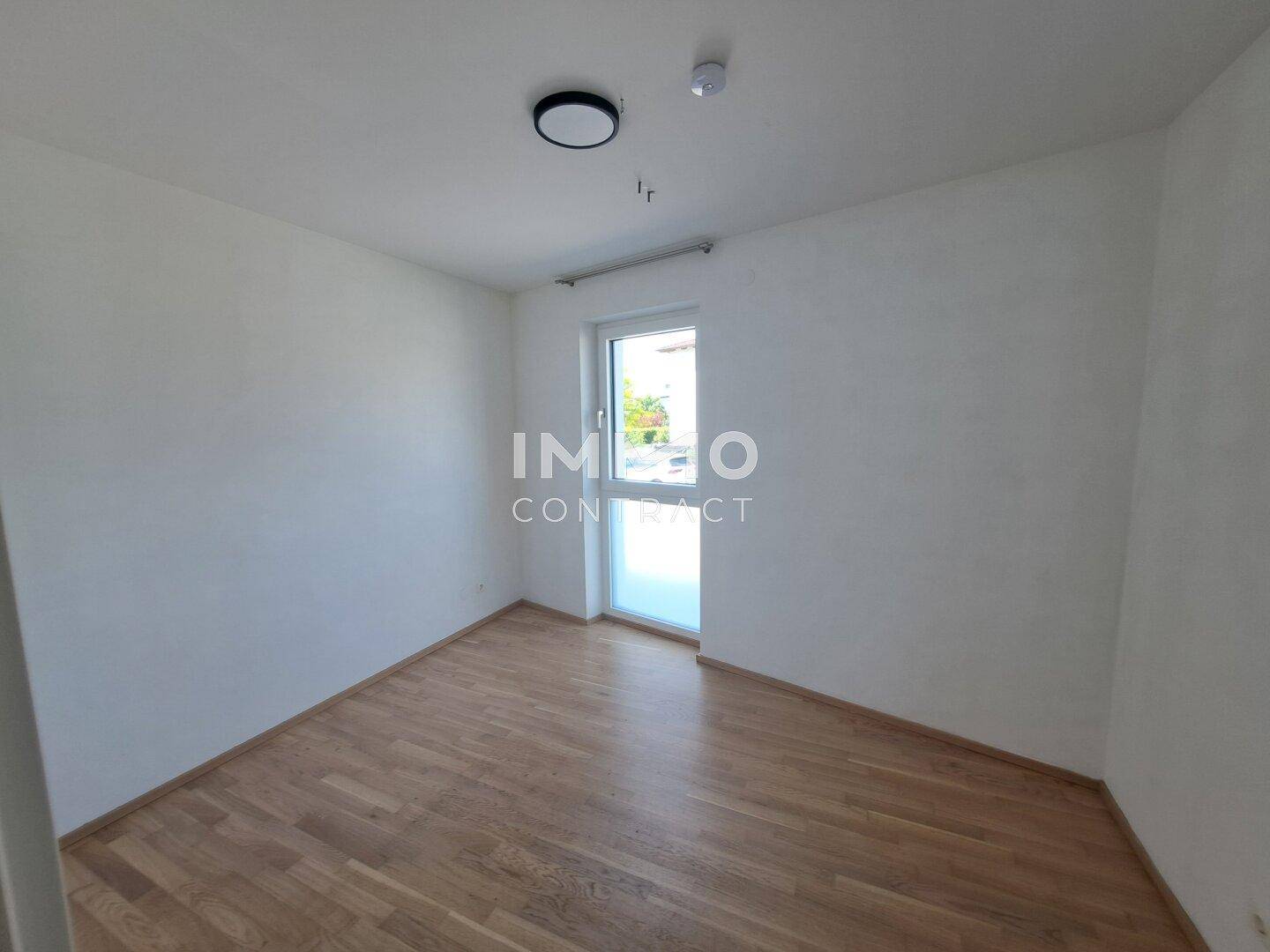 Helles Zimmer mit Holzfußboden und Fenster, ideal als Schlafzimmer oder Büro nutzbar.