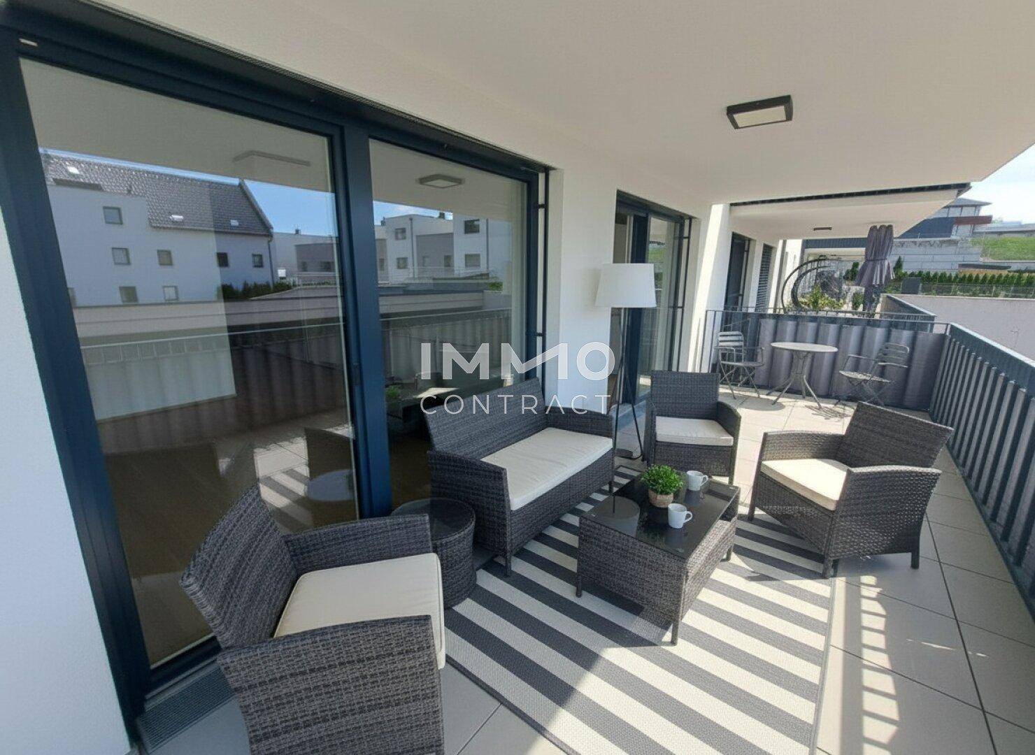 Möblierter Balkon mit bequemen Outdoor-Sitzmöbeln und einem gestreiften Teppich.