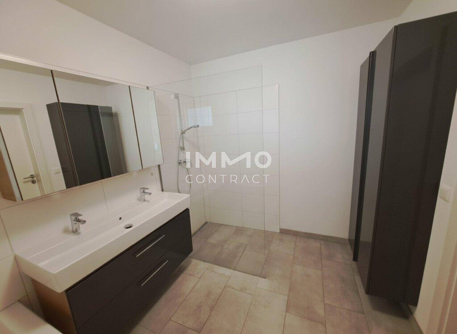 Modernes Badezimmer mit Doppelwaschbecken, Spiegelschrank und begehbarer Dusche.