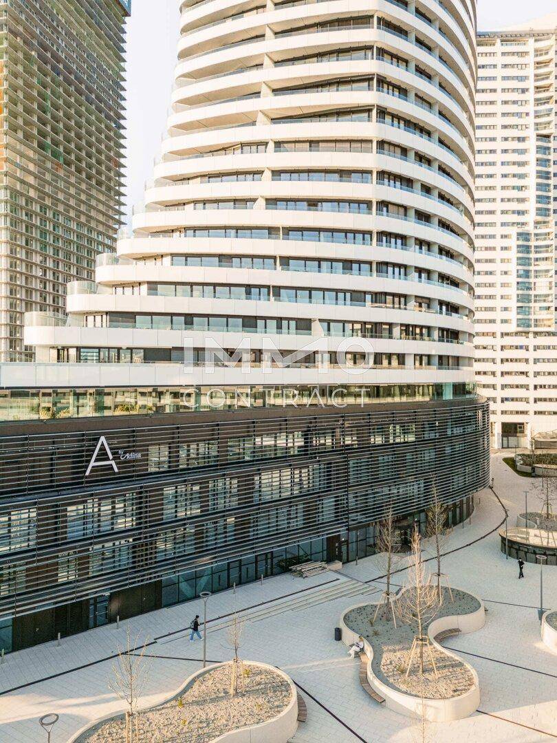 Moderner Gebäudekomplex mit geschwungener Architektur und einer öffentlichen Plaza im Vordergrund.