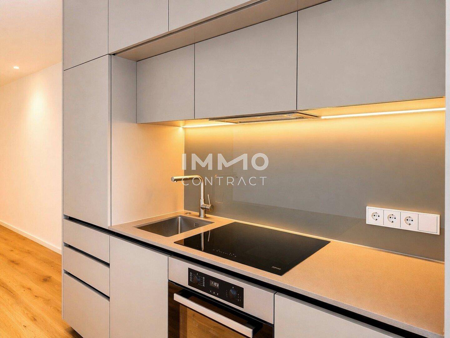 Moderne Küchenzeile mit grauen Schränken, Induktionskochfeld und integriertem Backofen.