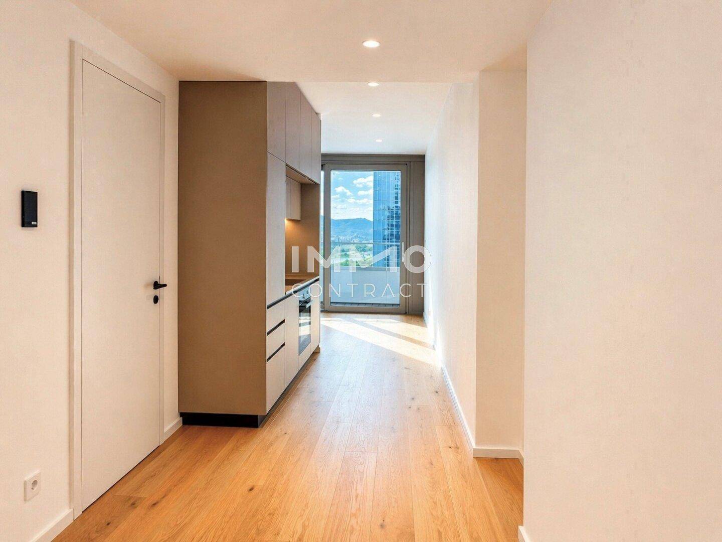 Heller Flur mit integrierter Küchenzeile und Zugang zu einem Balkon oder großen Fenster.