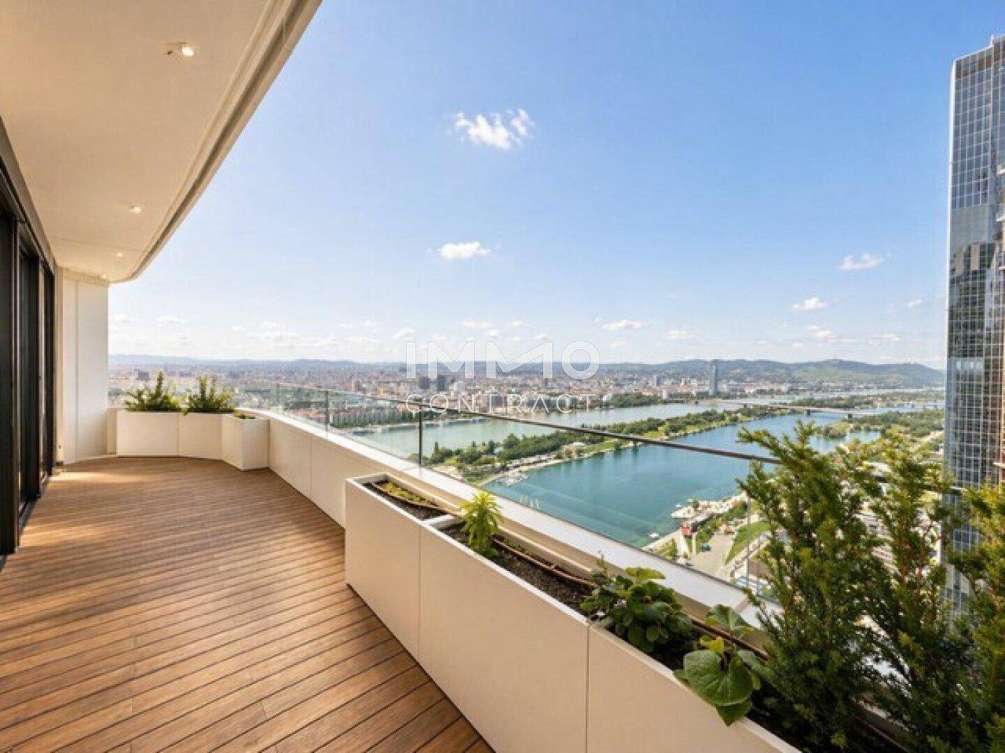 Geräumige Terrasse mit Holzboden, Pflanzen und weitem Blick über die Stadt und den Fluss.