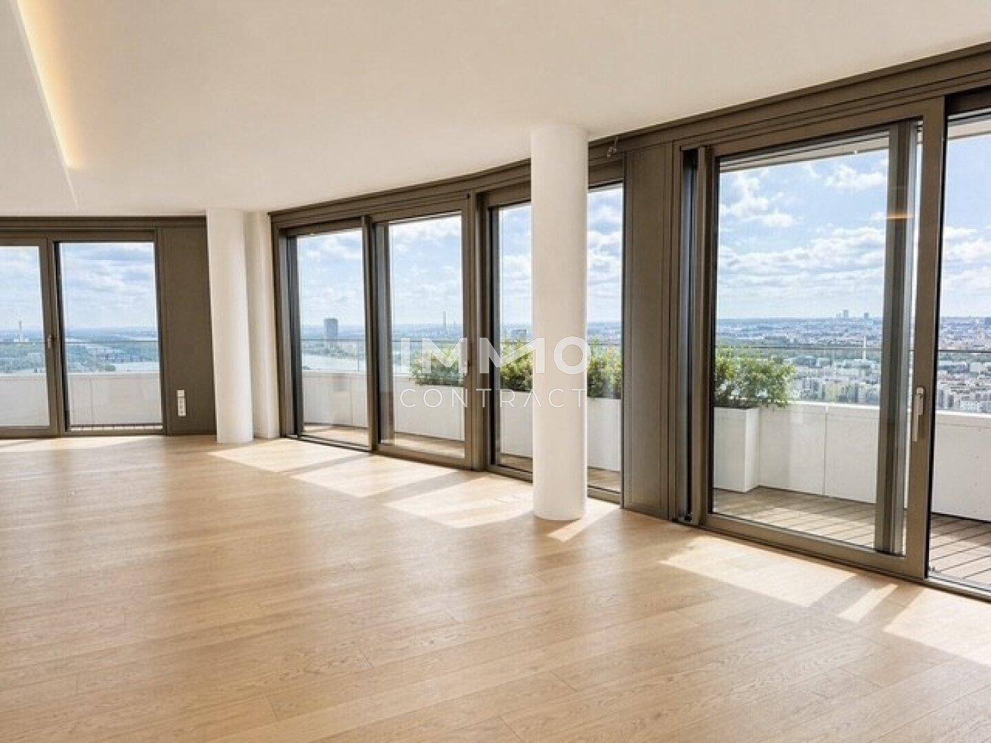 Heller Wohnbereich mit Holzboden und geschwungenen Panoramafenstern, die auf einen Balkon führen.