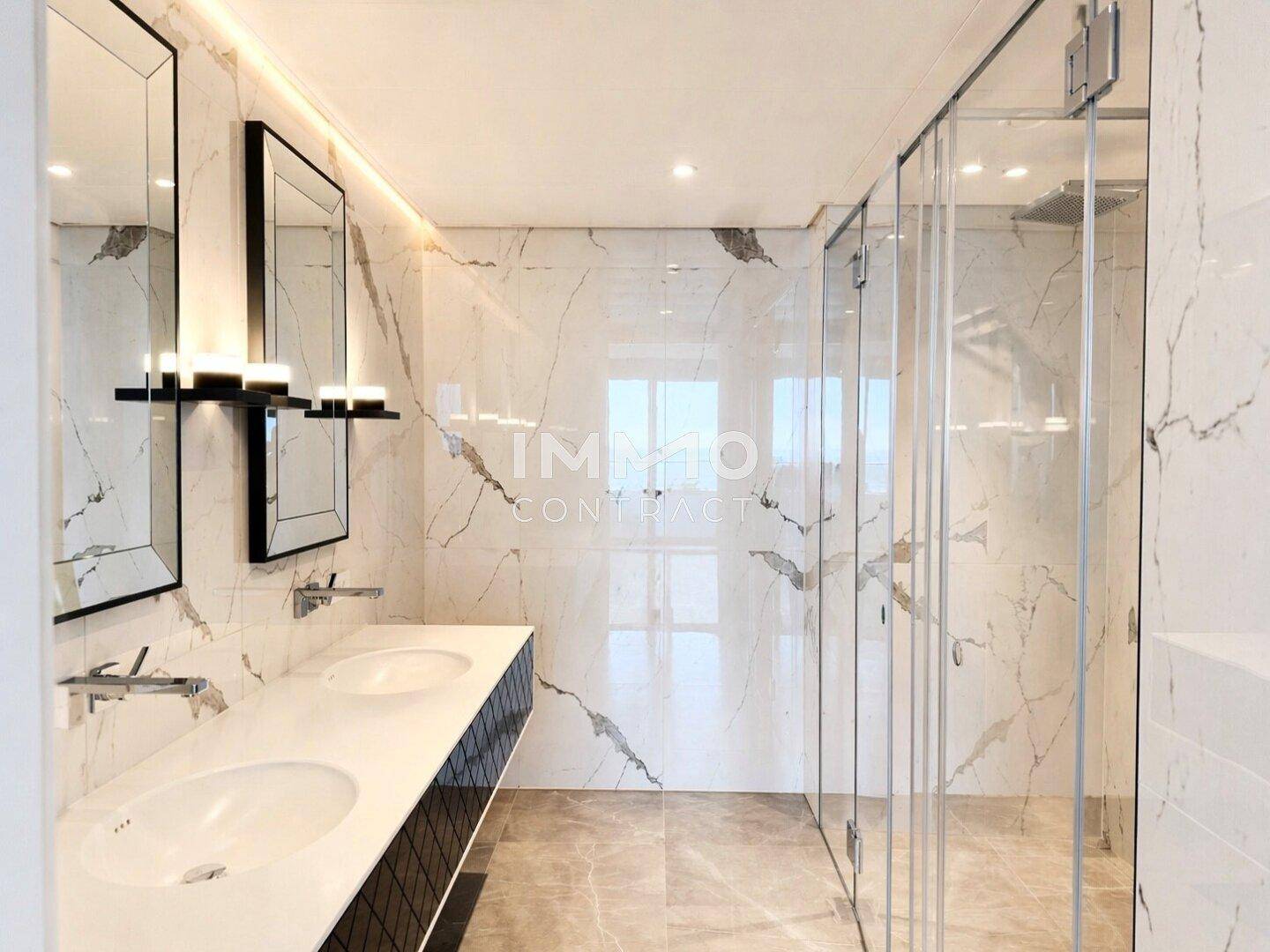 Luxuriöses Badezimmer mit Marmorwänden, Doppelwaschbecken und großer begehbarer Dusche.