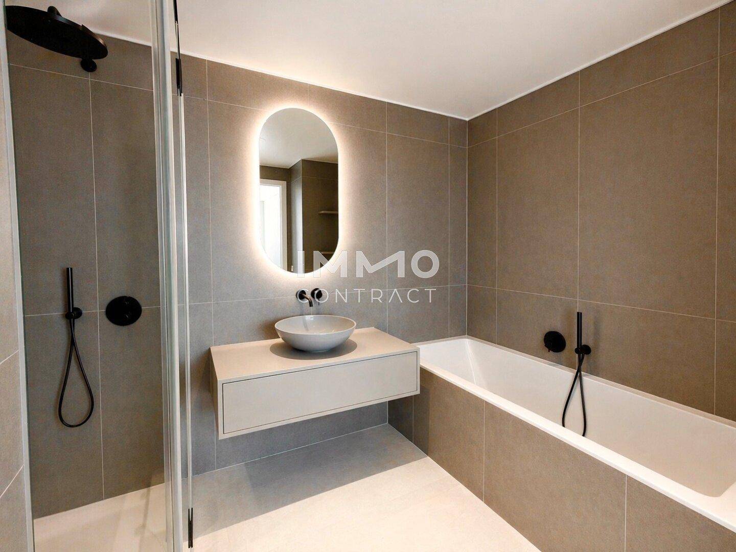 Modernes Badezimmer mit grauen Fliesen, einer Badewanne und einer begehbaren Dusche.