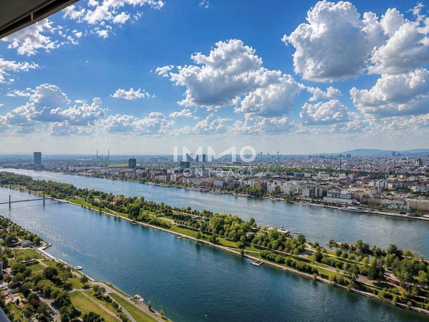 Weitläufiger Blick auf die Stadt und den Fluss mit üppigem Grün unter einem strahlend blauen Himmel.