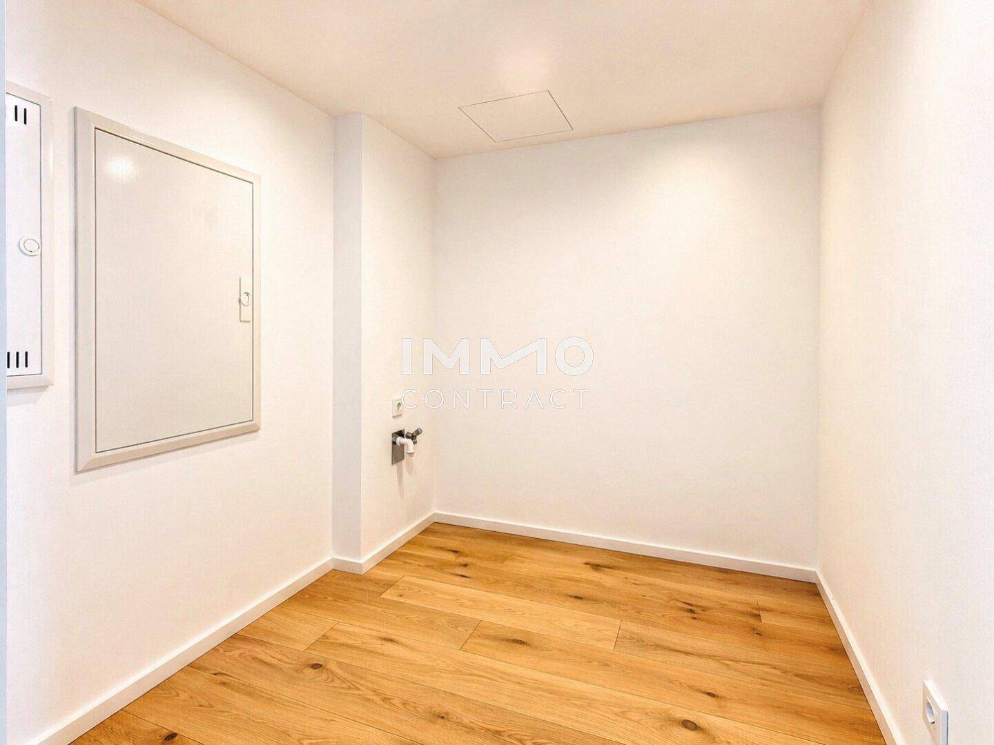 Kleiner, heller Raum mit weißen Wänden und Holzboden, ideal als Abstellraum oder Hauswirtschaftsraum.