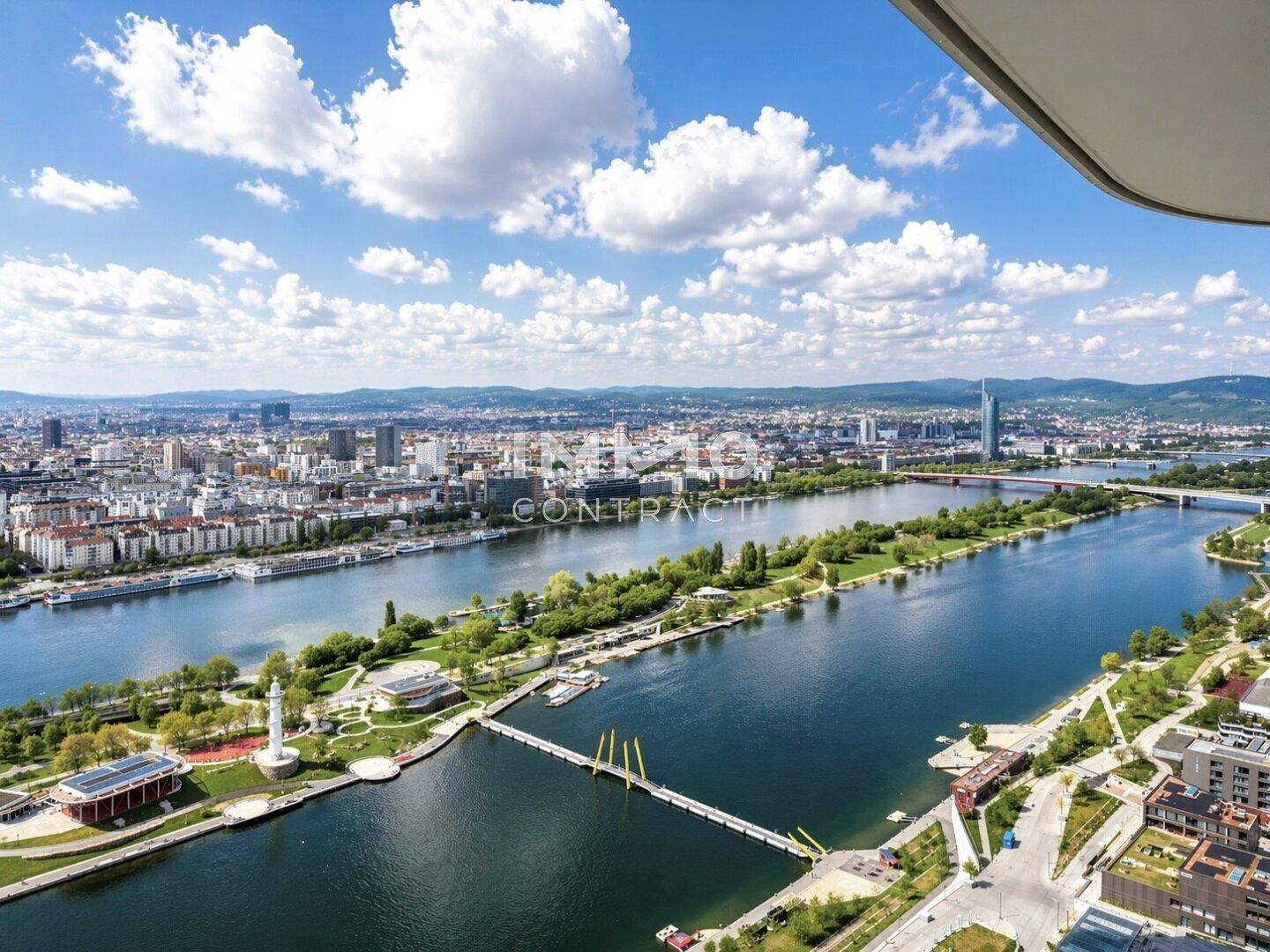 Panoramablick auf die Stadt mit dem Fluss, Brücken und einem Leuchtturm unter blauem Himmel.