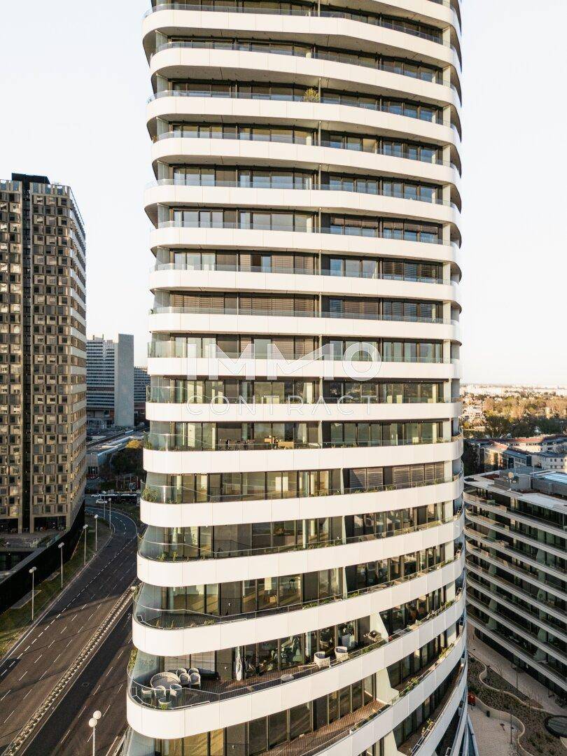Detailansicht eines elegant geschwungenen Hochhauses mit zahlreichen Balkonen und Glasfassaden.
