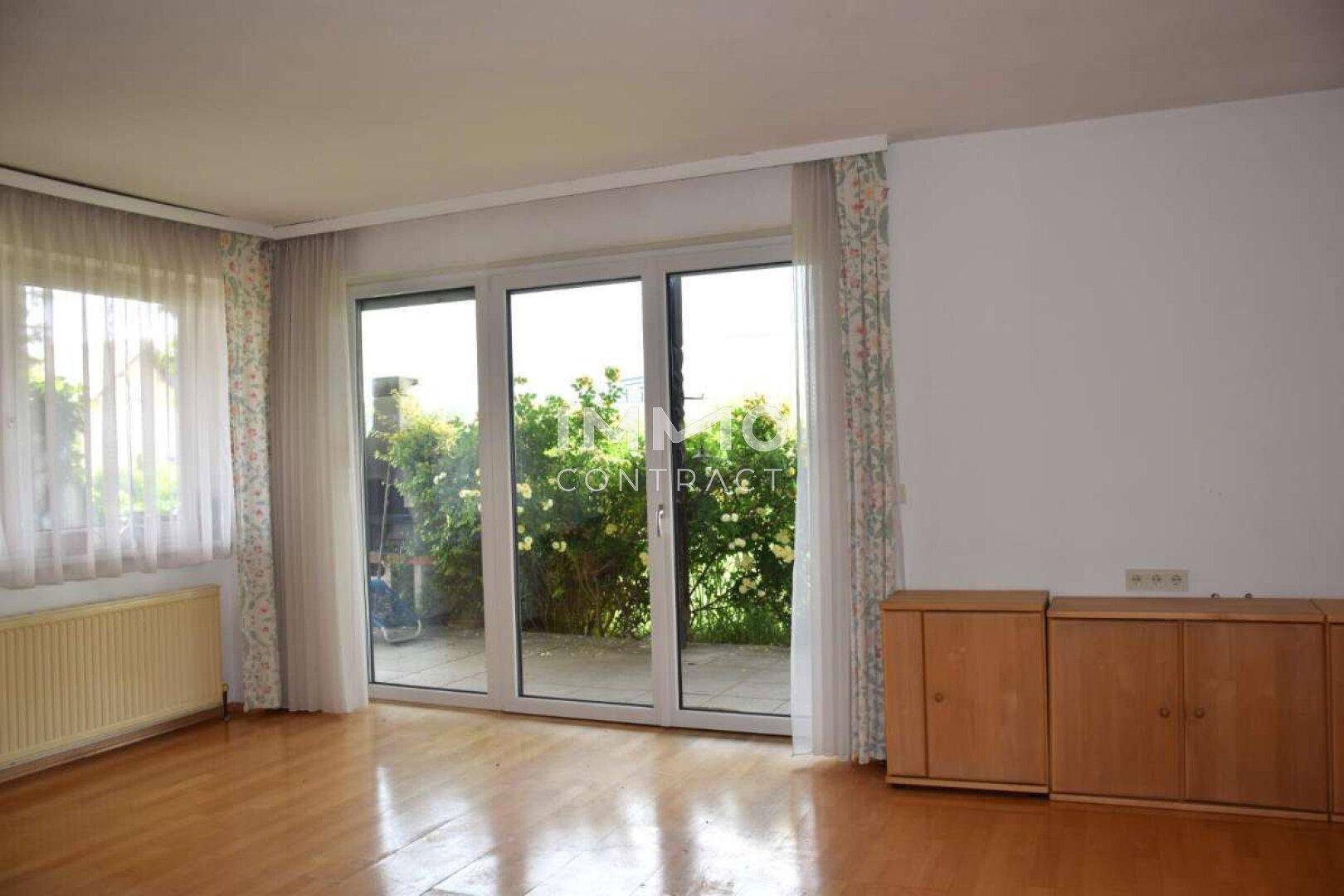 Helles Wohnzimmer mit Parkettboden und großen Schiebetüren, die zur Terrasse führen.