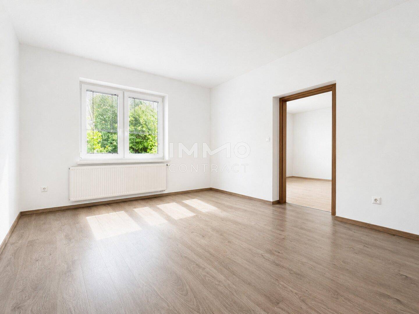 Heller Raum mit Laminatboden, weißen Wänden und viel Tageslicht durch das Fenster.