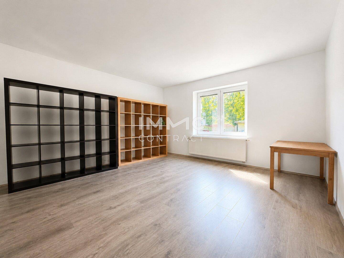 Vielseitiger Raum mit Regalsystemen, grauem Laminatboden und hellem Fenster.