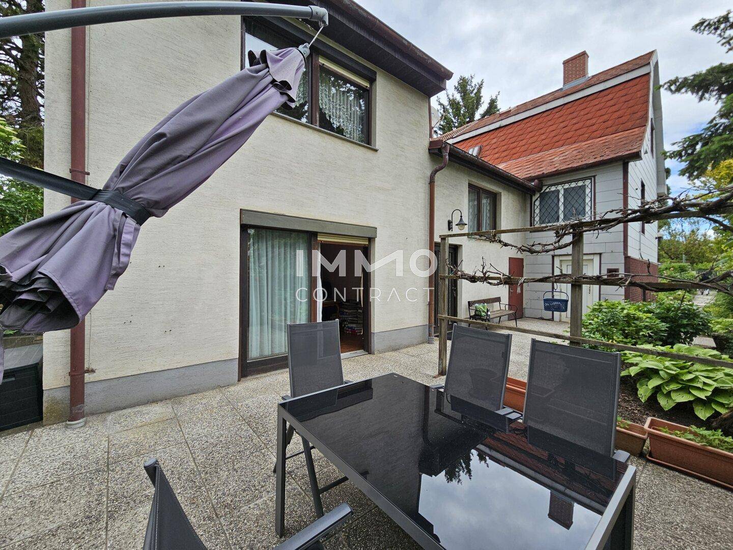 Geräumige Terrasse mit Esstisch und Stühlen, ideal für Mahlzeiten im Freien am Haus.