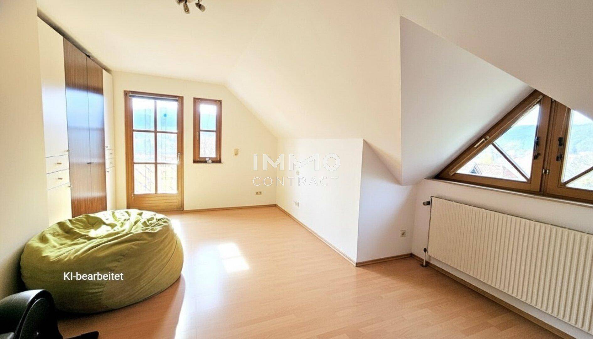 Helles Schlafzimmer im Dachgeschoss mit Dachschrägen, Holzboden und Balkonzugang.