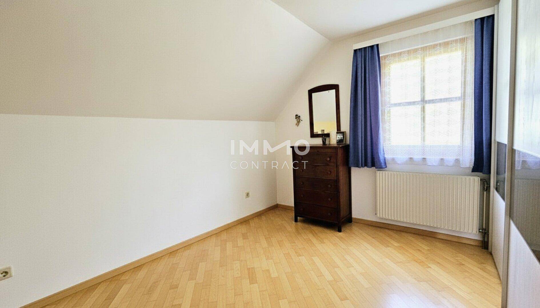 Ruhiges Schlafzimmer im Dachgeschoss mit Dachschrägen, Holzboden und Fenster.