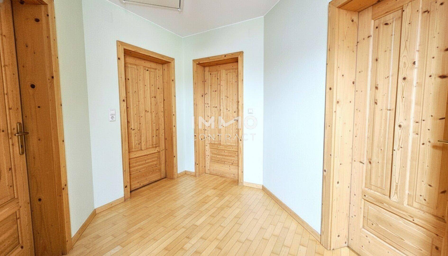 Heller Flur mit Holztüren und Parkettboden, der zu verschiedenen Räumen führt.