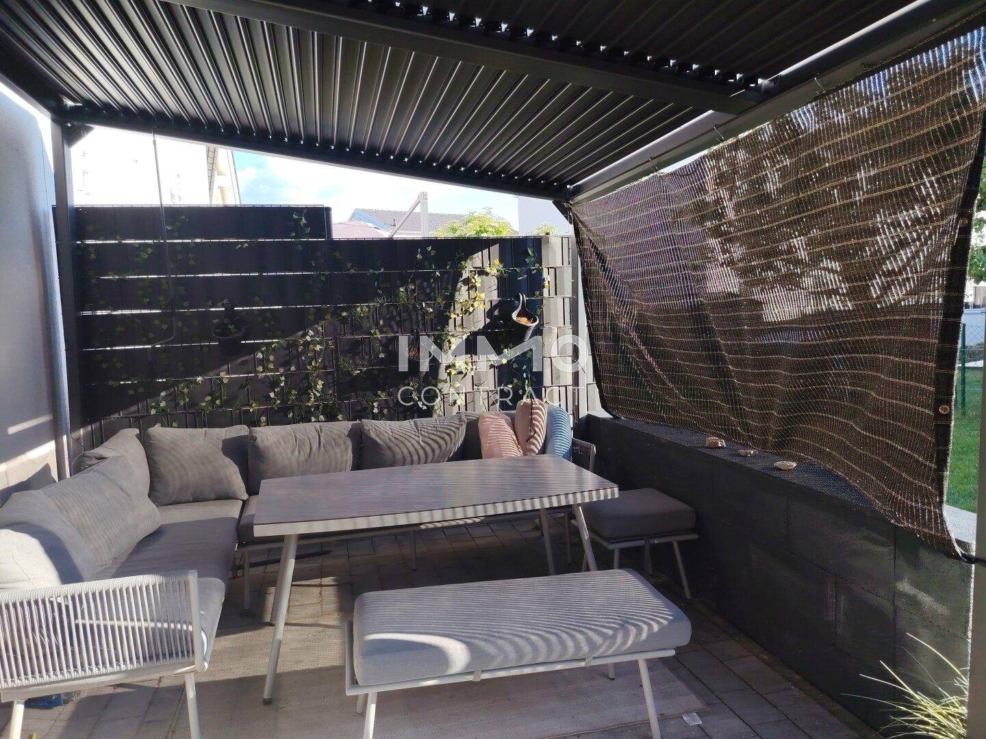 Überdachte Terrasse mit bequemen Gartenmöbeln und Sichtschutz für Privatsphäre.