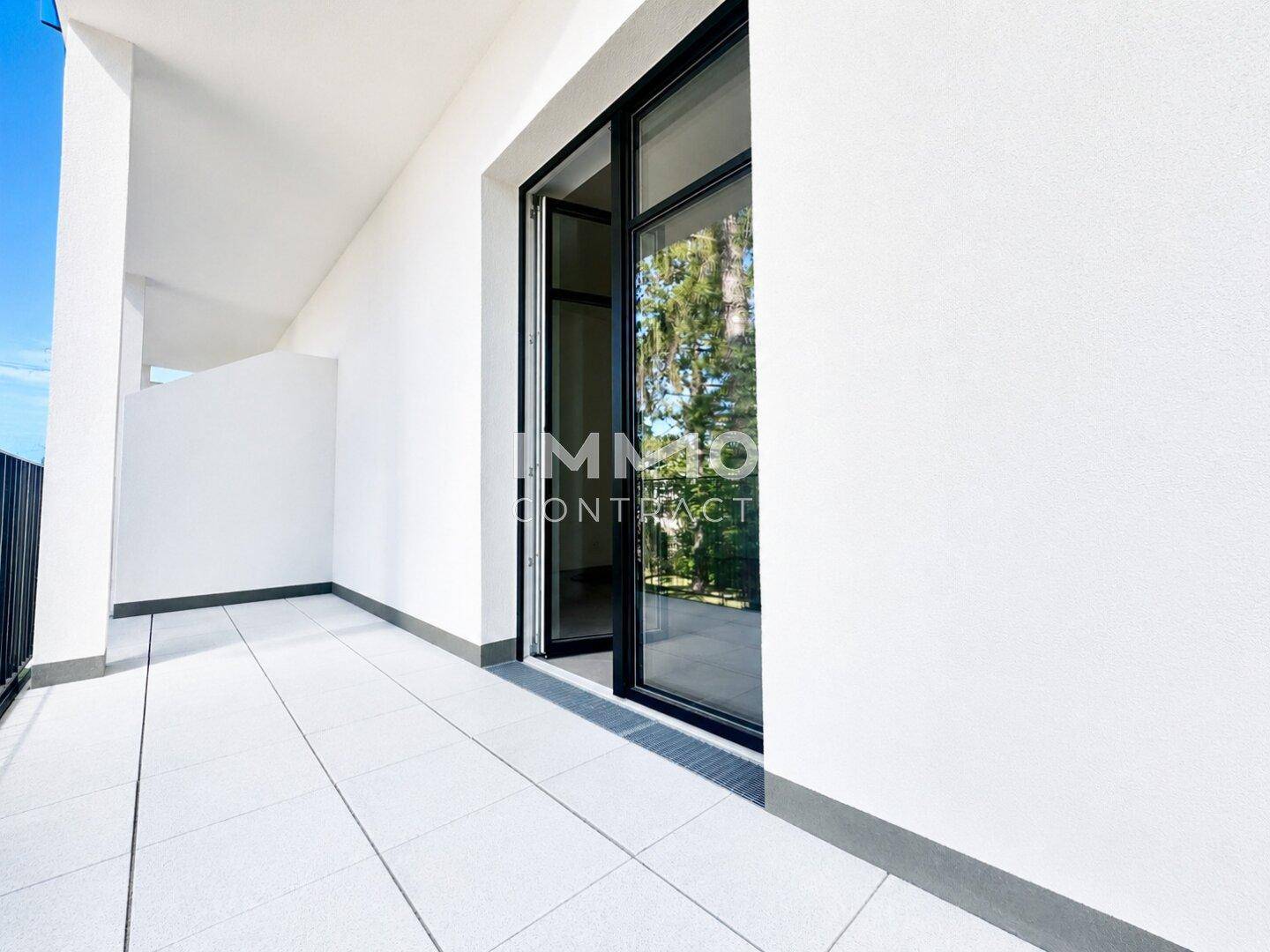 Geräumiger Balkon mit hellen Fliesen und großen Schiebetüren zum Innenbereich.