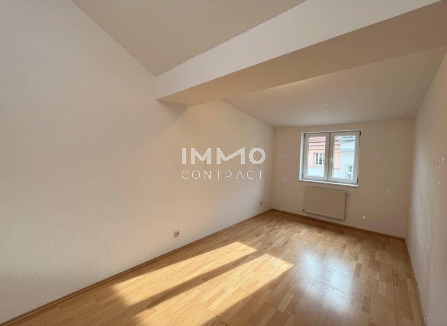 Heller Raum mit Parkettboden und Dachschräge, geeignet als Schlaf- oder Arbeitszimmer.