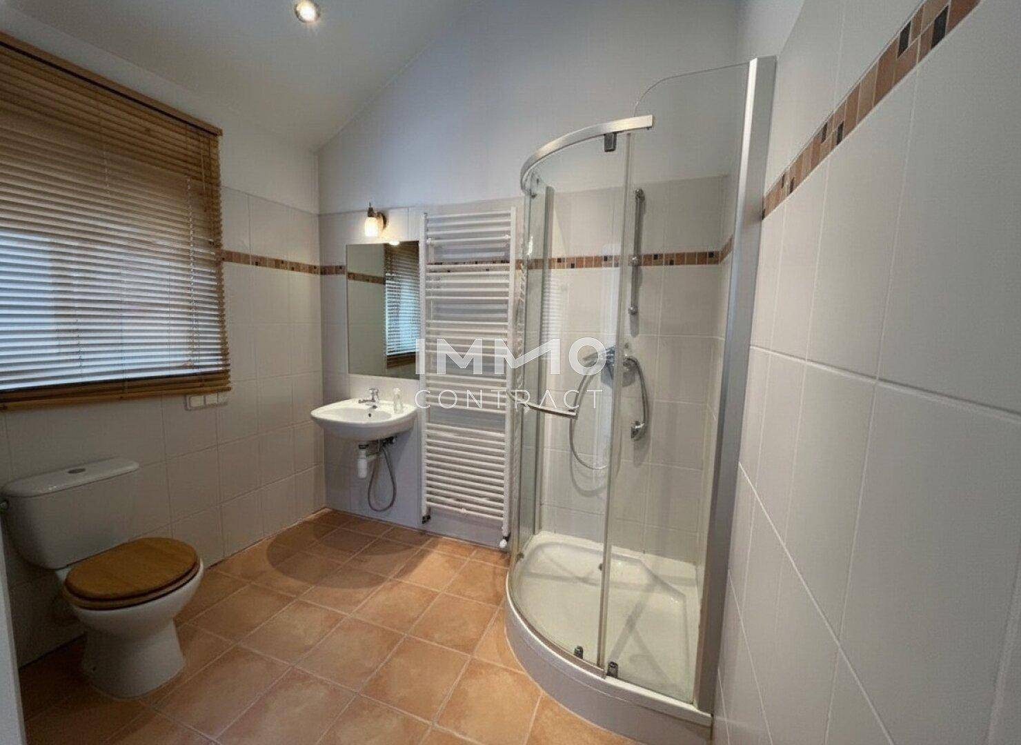 Funktionales Badezimmer mit Duschkabine, Waschbecken, WC und beheiztem Handtuchhalter.