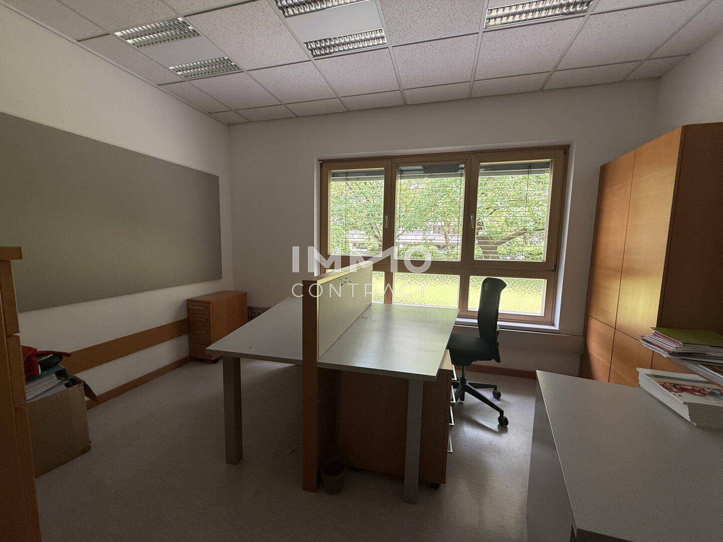 Büro mit zwei Arbeitsplätzen, Aktenschränken und Blick auf die grüne Umgebung.