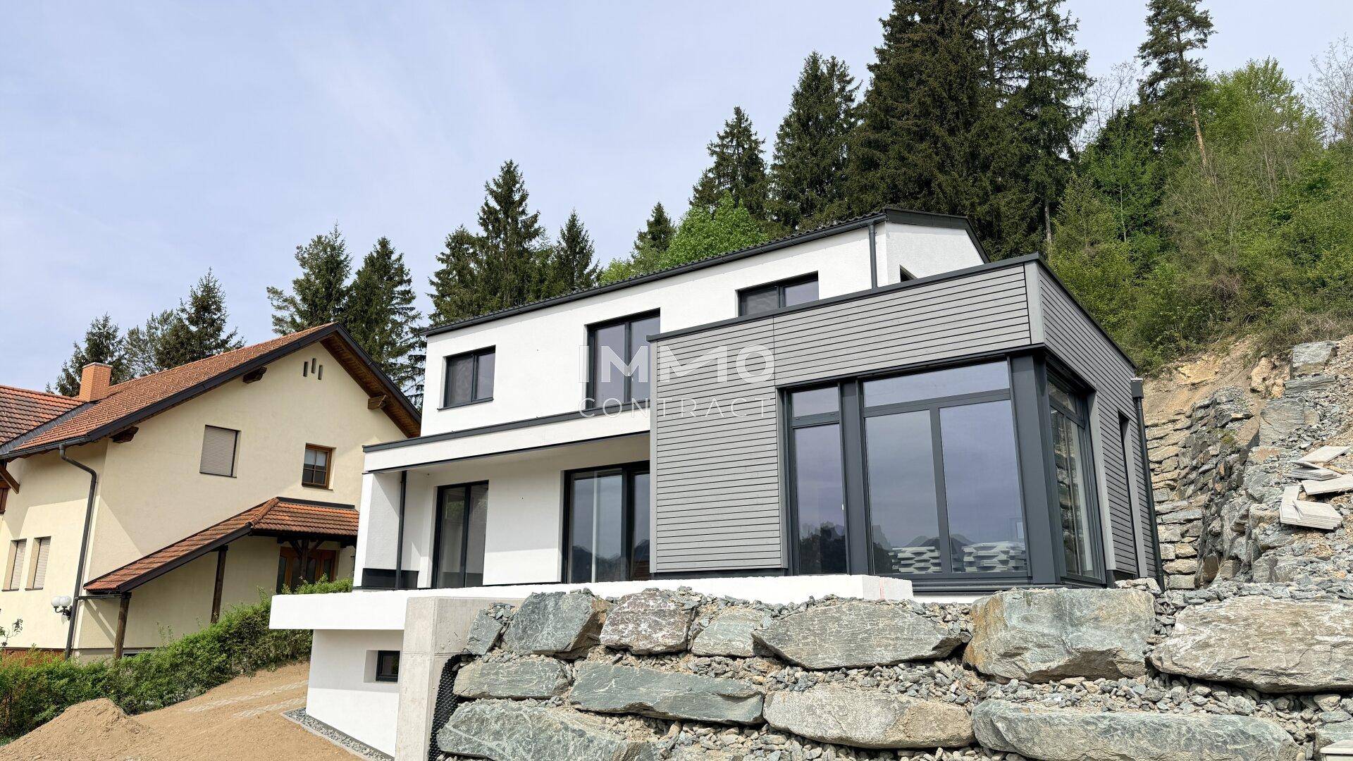 Modernes Einfamilienhaus am Hang mit zeitgenössischer Architektur und großen Fensterfronten.