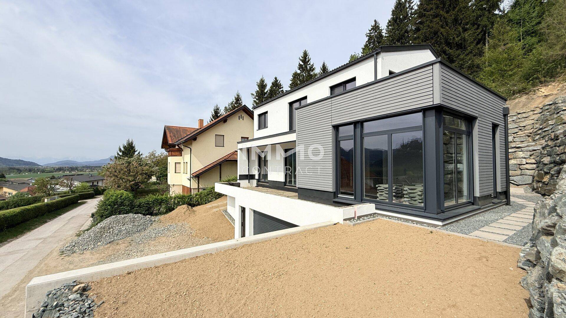 Modernes Haus in Hanglage mit weitem Blick über die Landschaft und die umliegenden Berge.