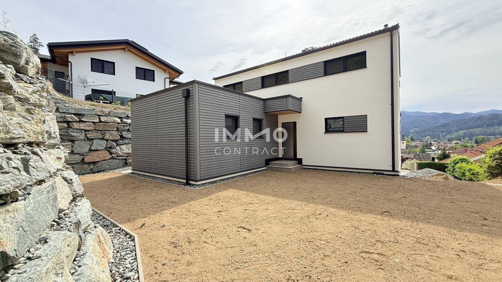 Rückansicht des modernen Hauses mit vorbereitetem Gartenbereich und Blick auf die Umgebung.