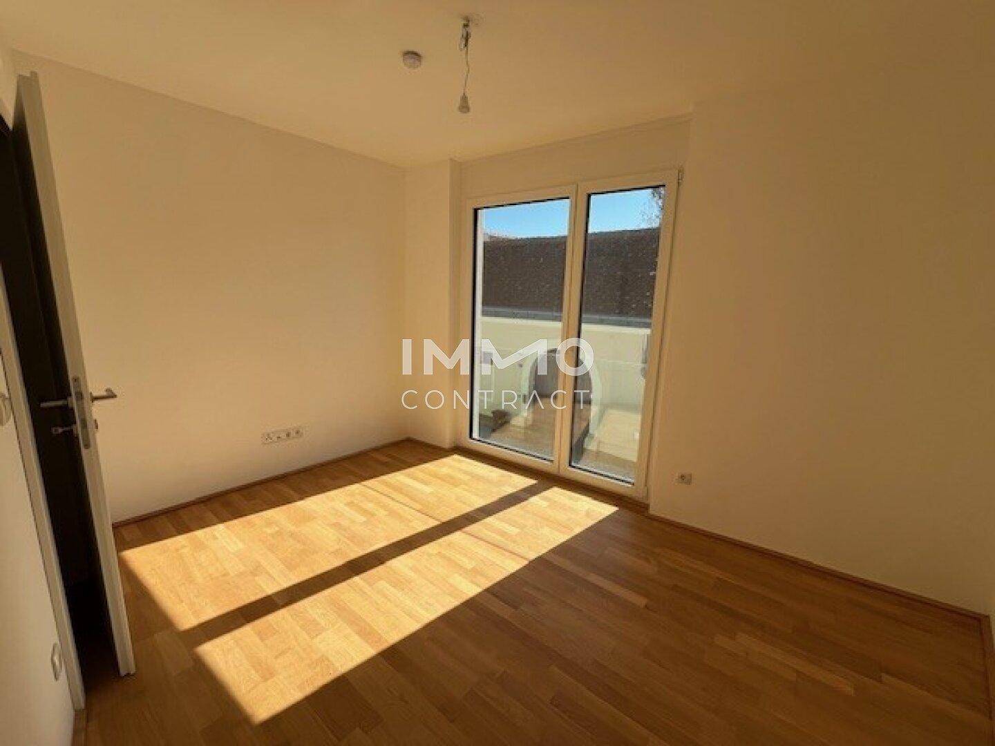 Helles Schlafzimmer mit Parkettboden und Zugang zu einem Außenbereich, ideal für Entspannung.
