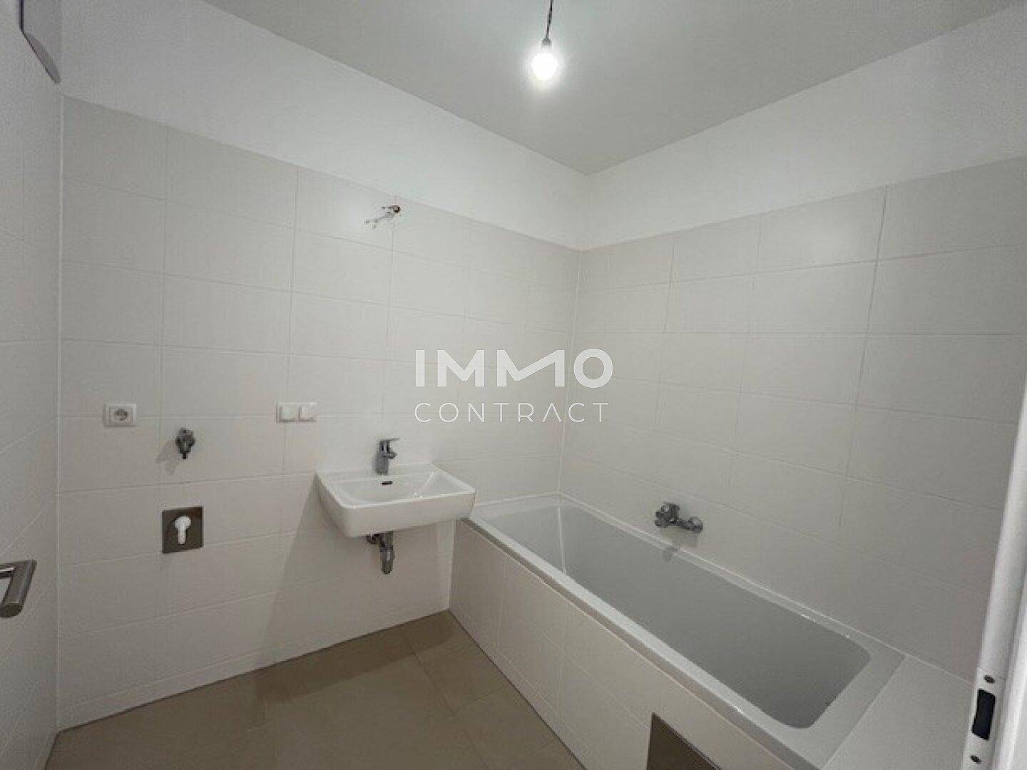 Modernes Badezimmer mit Badewanne, Waschbecken und weißen Fliesen, bereit zur individuellen Gestaltung.
