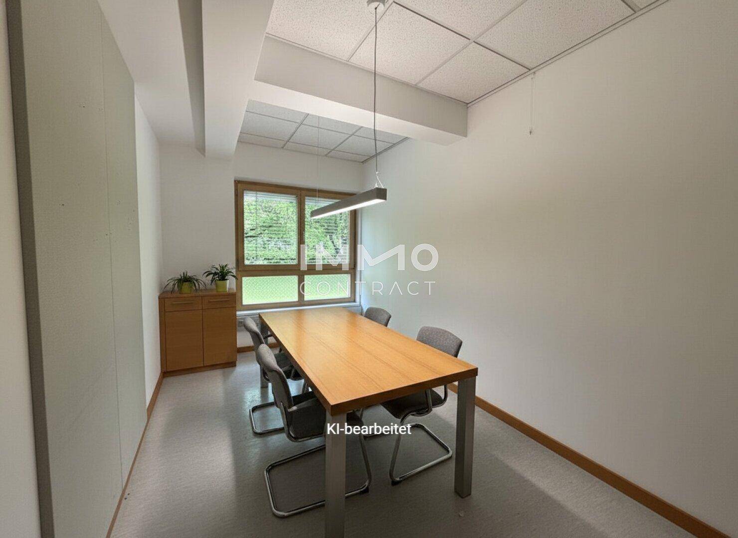 Konferenzraum mit Holztisch, Stühlen und Fenster mit Blick ins Grüne.