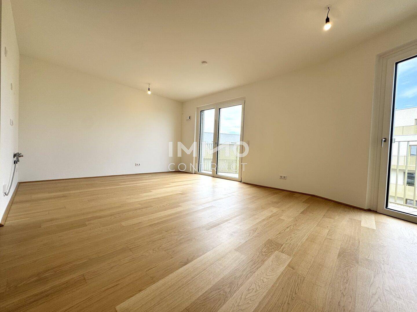 Geräumiges, unmöbliertes Zimmer mit Parkettboden und großen Fenstern für viel Tageslicht.