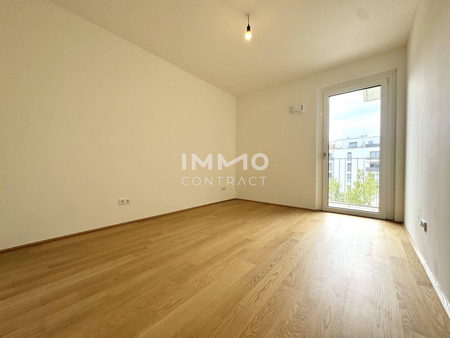 Helles Schlafzimmer mit Holzboden und Zugang zu einem französischen Balkon.