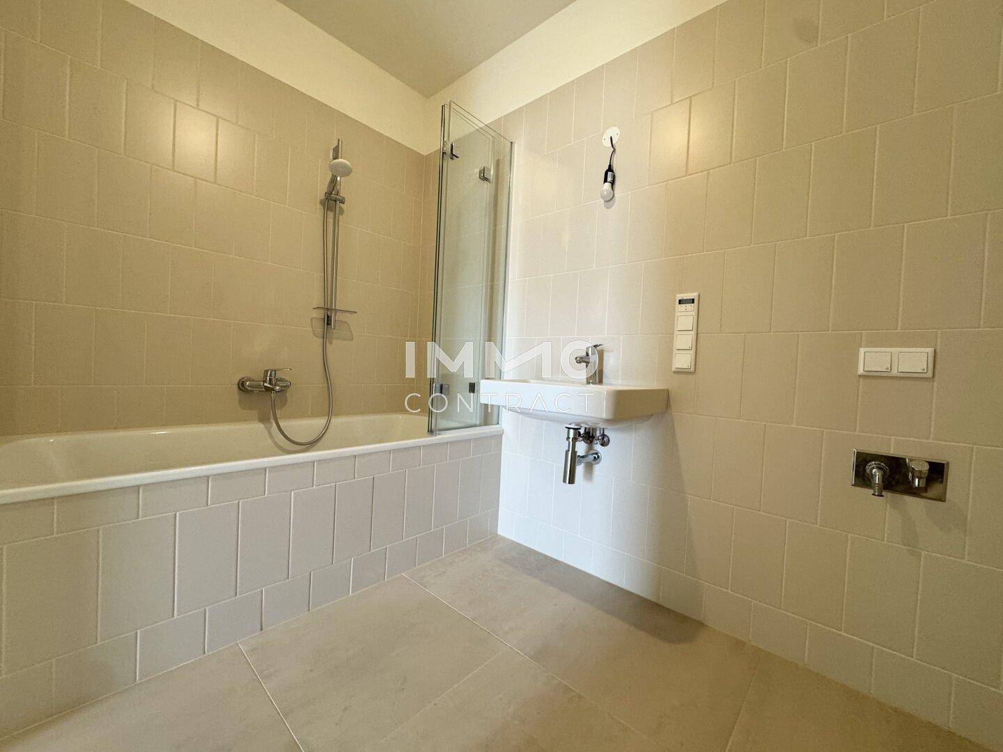 Modernes Badezimmer mit Badewanne, Duschwand und einem einzelnen Waschbecken.