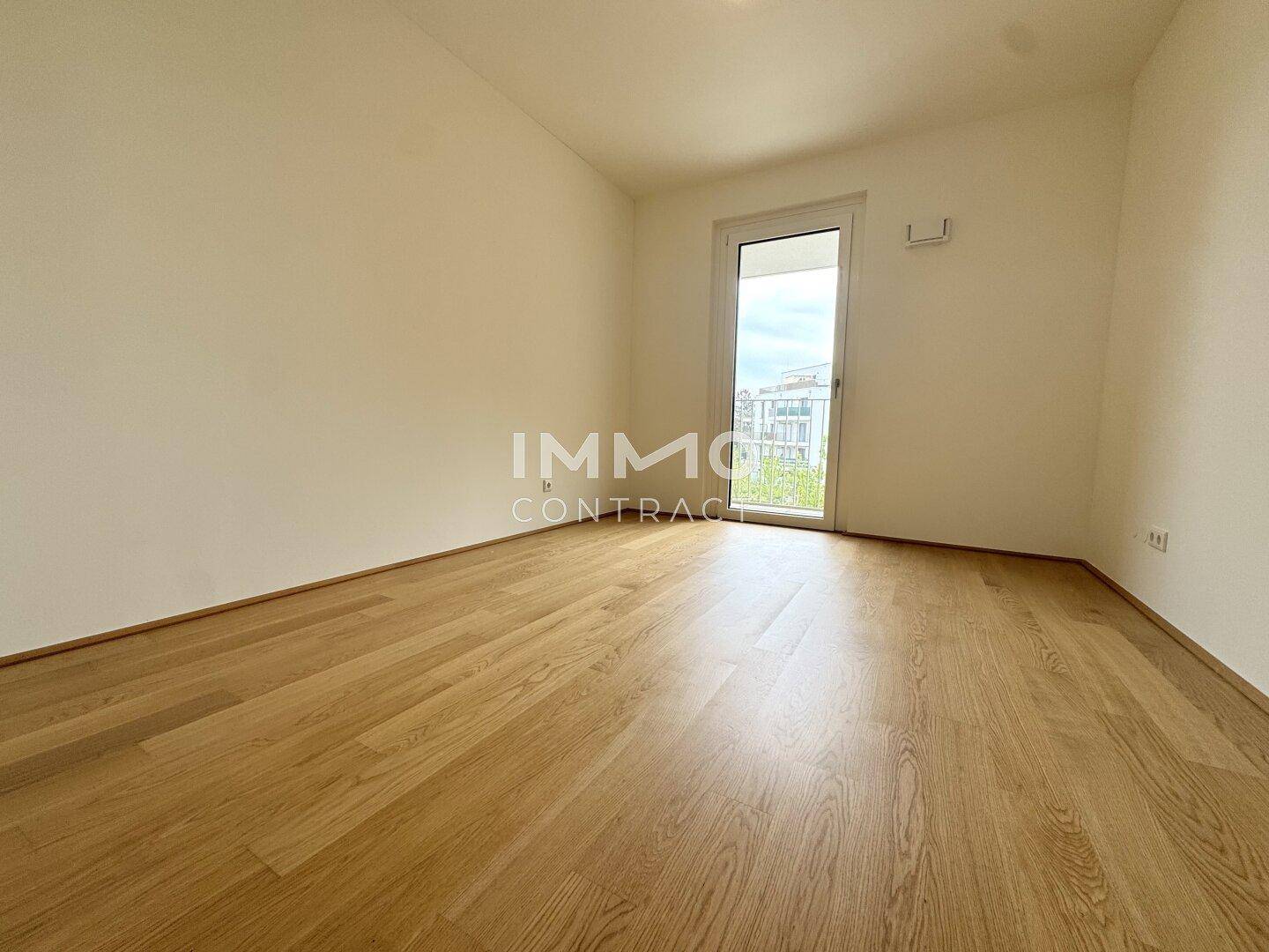 Geräumiges Schlafzimmer mit hellem Holzboden und Zugang zu einem Außenbereich.