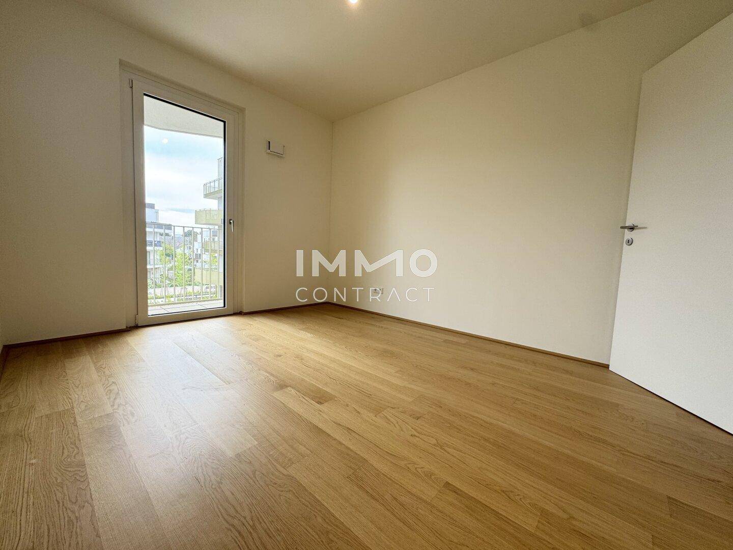 Unmöbliertes Schlafzimmer mit Parkettboden und Balkontür, bereit zur persönlichen Einrichtung.