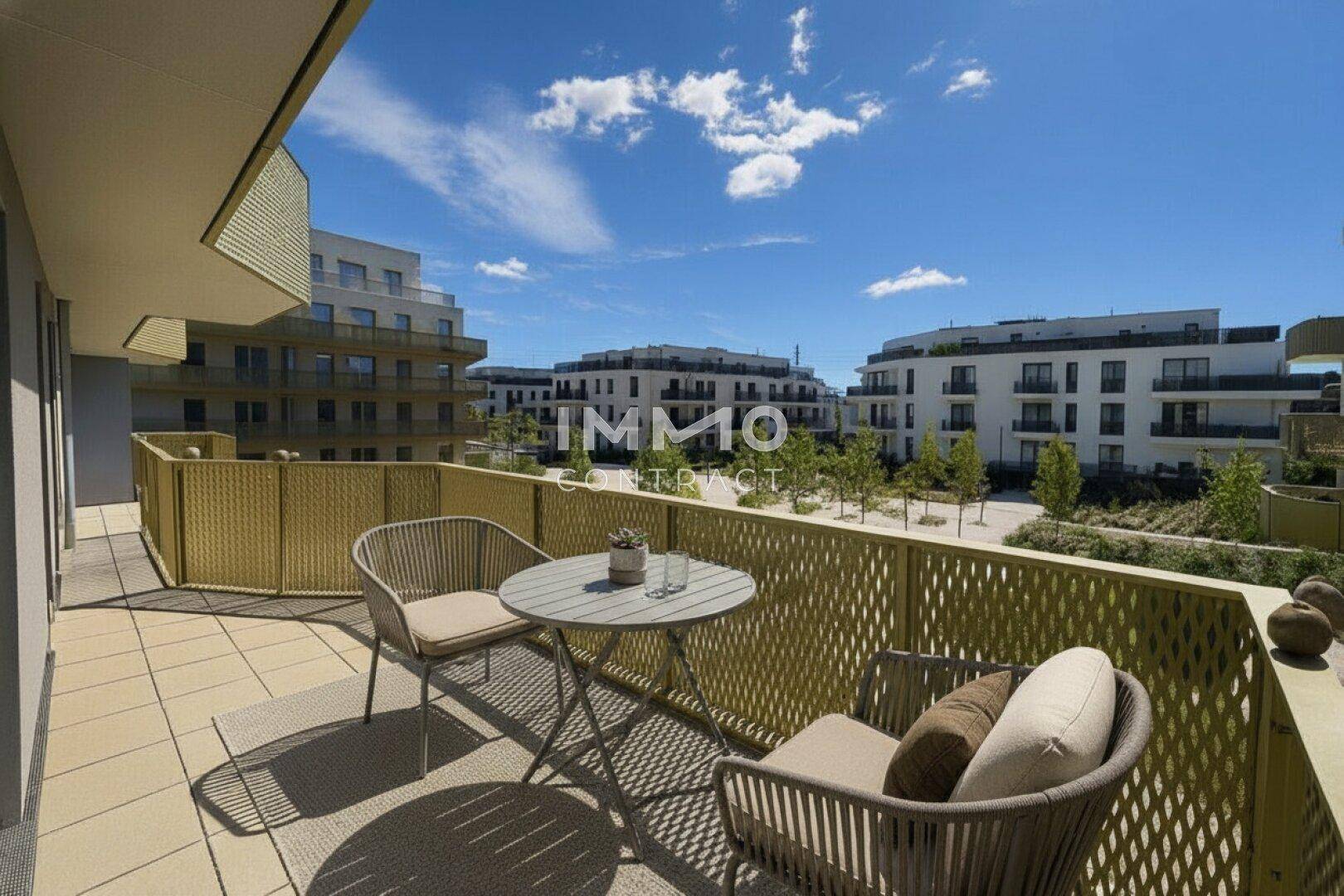 Geräumiger Balkon mit Sitzgelegenheiten und Blick auf die moderne Wohnanlage.