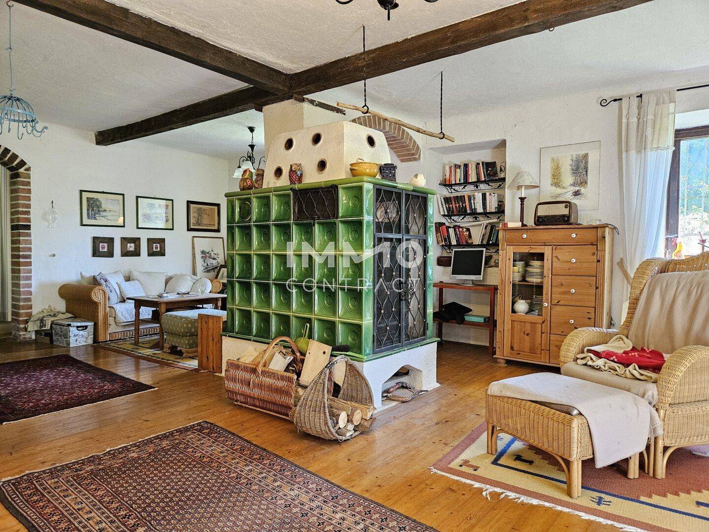 Geräumiges Wohnzimmer mit traditionellem Kachelofen, Holzbalken und rustikalen Möbeln, sehr gemütlich.