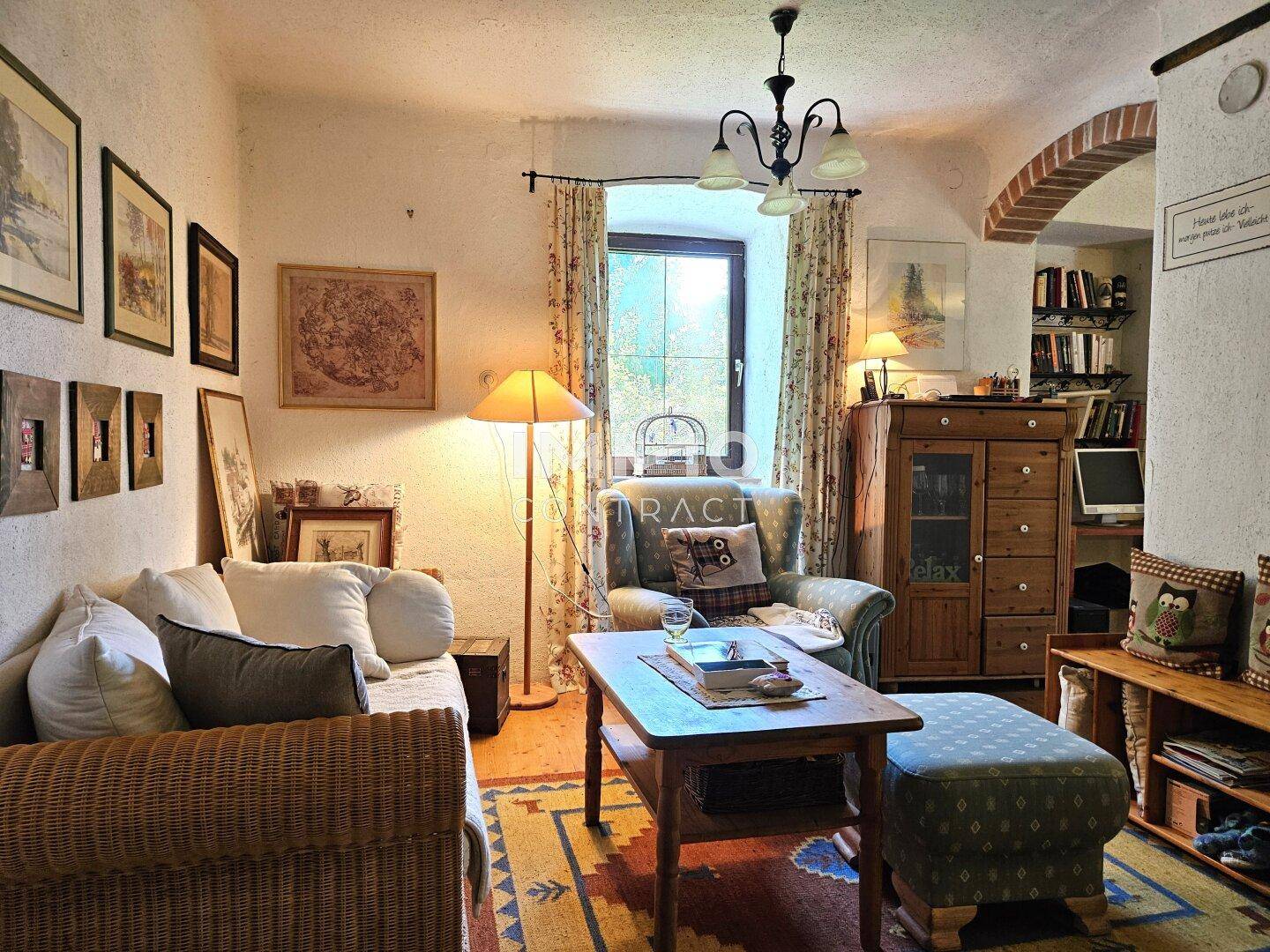Kleines, gemütliches Wohnzimmer mit rustikalen Möbeln, einem Fenster und vielen Bildern an der Wand.