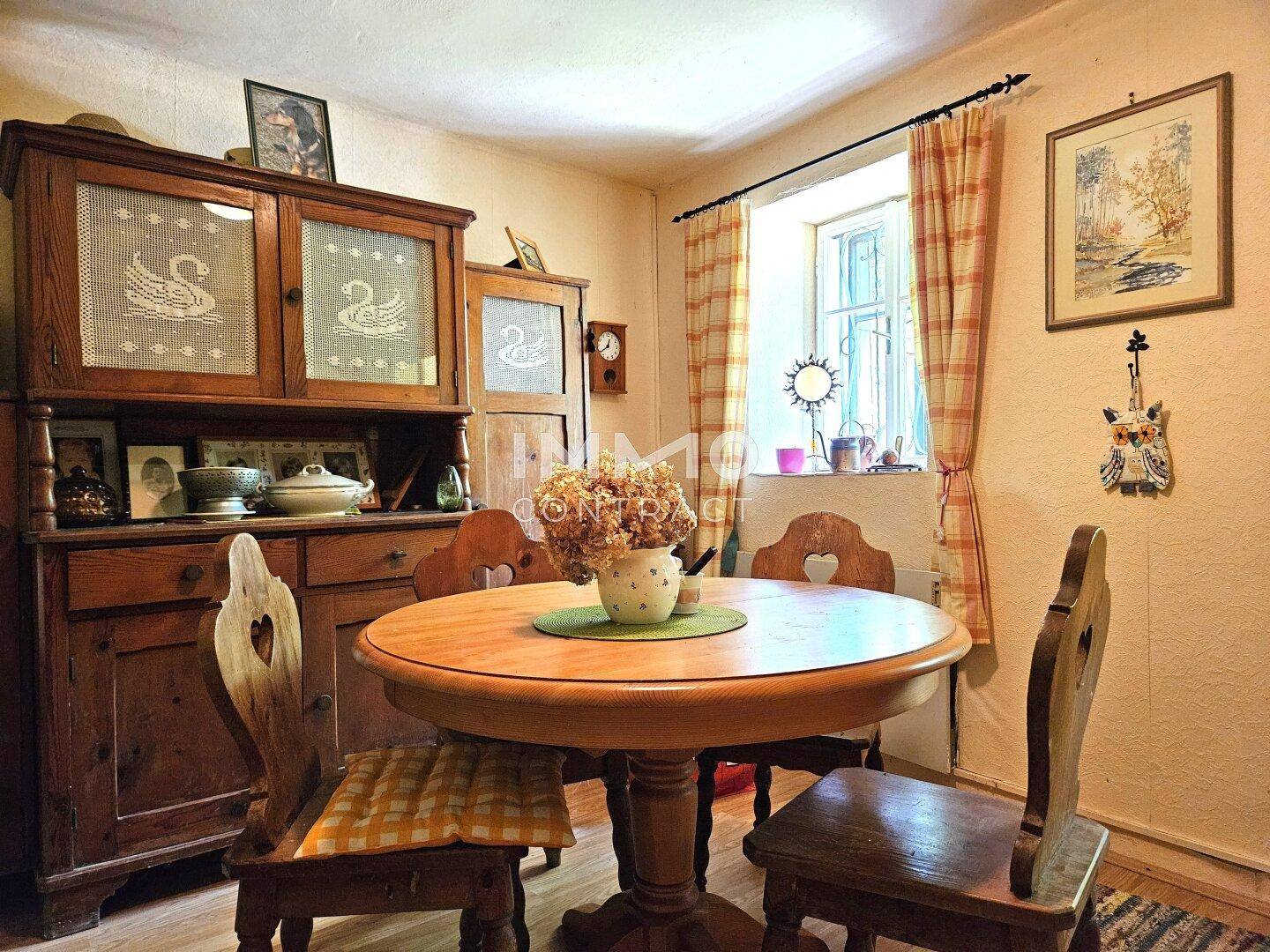 Rustikaler Essbereich mit rundem Holztisch, traditionellen Stühlen und einem antiken Schrank.