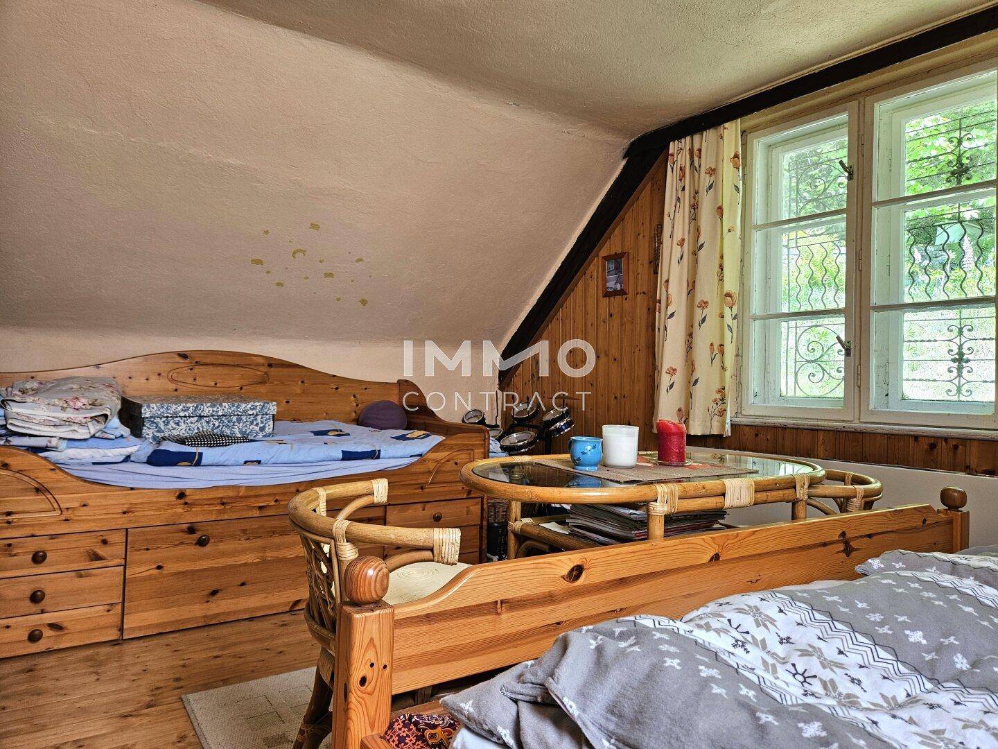 Schlafzimmer mit Holzbetten und Stauraum, Holzboden und einem Fenster mit Blick ins Grüne.