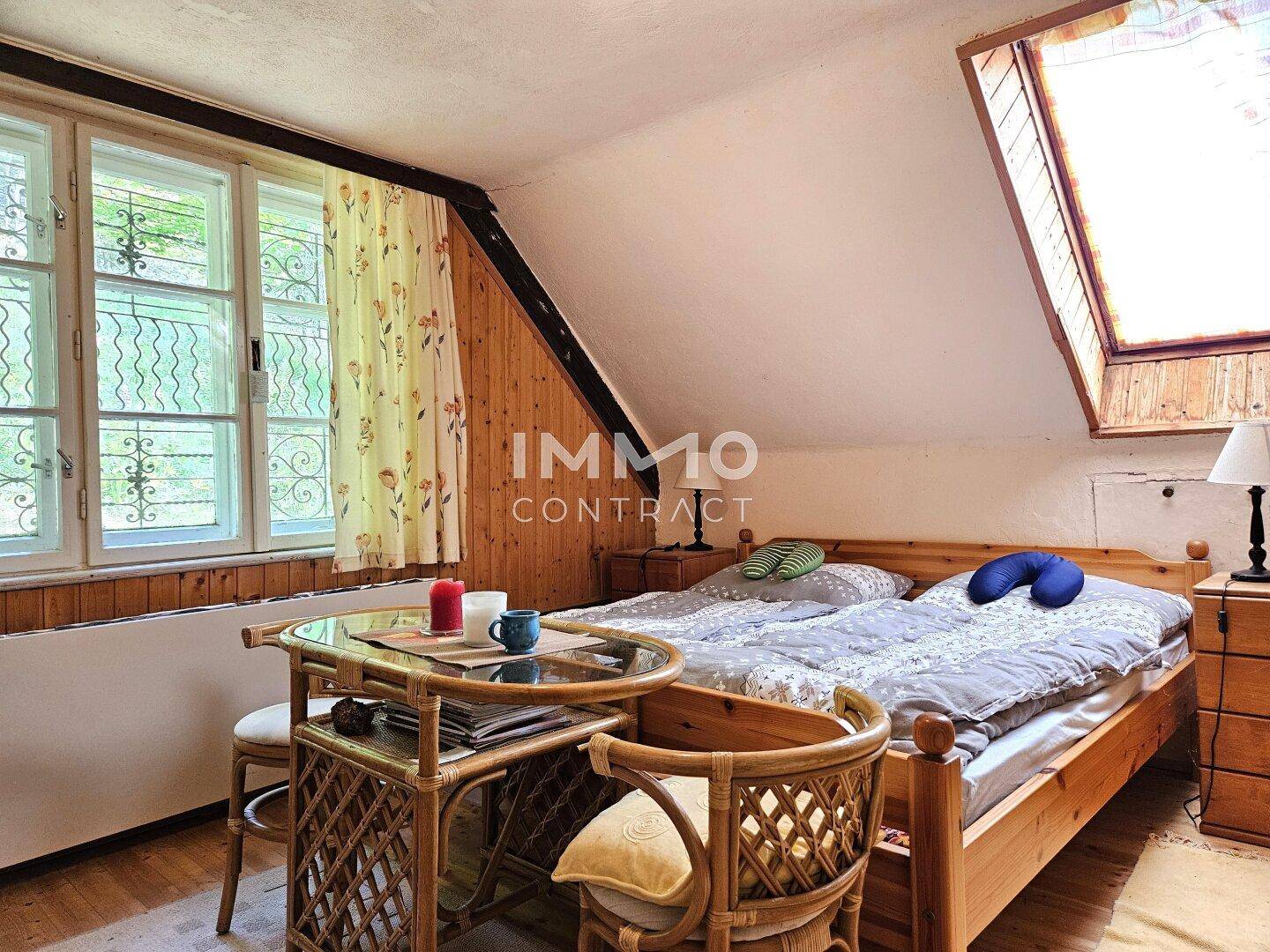 Schlafzimmer mit zwei Einzelbetten, Holzboden und einem Dachfenster, sehr hell und einladend.