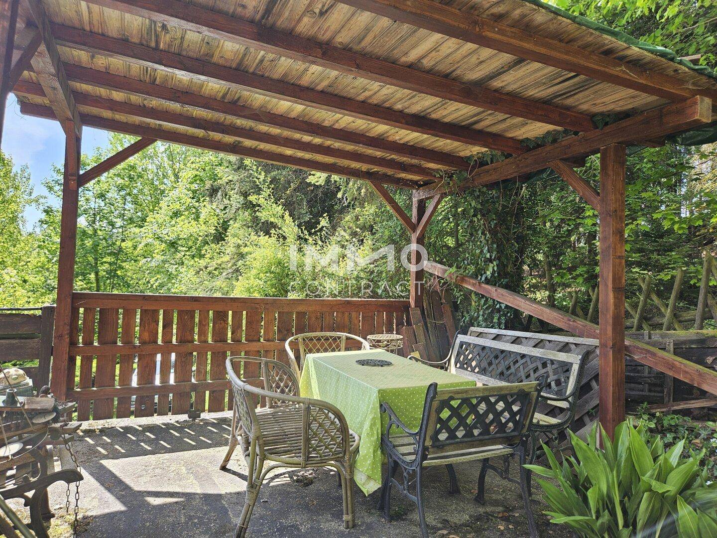 Überdachte Holzterrasse mit Gartenmöbeln, ideal für entspannte Stunden im Freien.